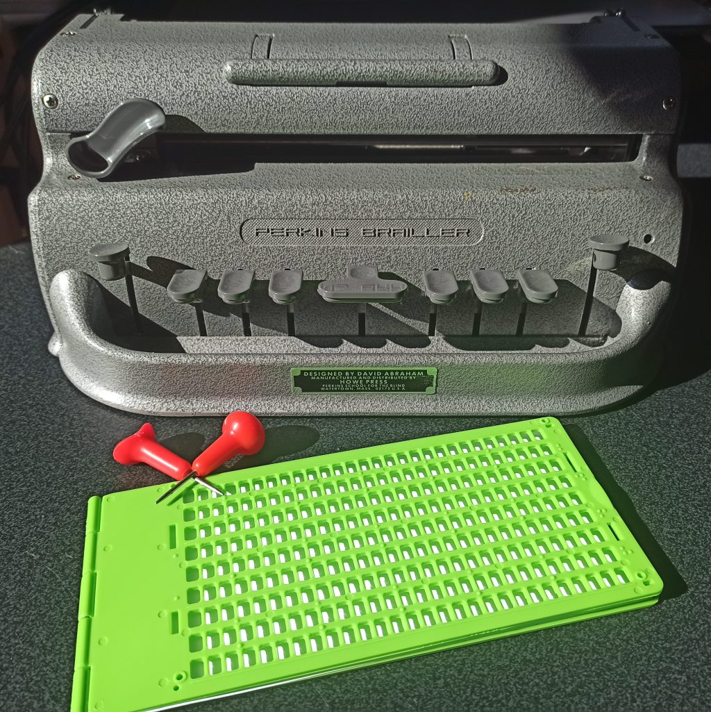 a perkins brailler, a couple of styluses and a slate