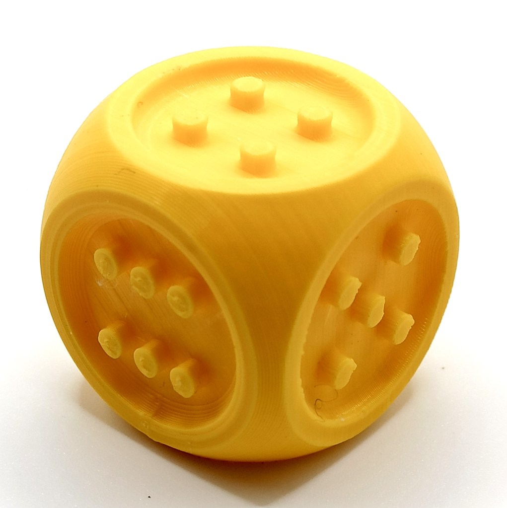 a 3D printed yellow dice with raised dots