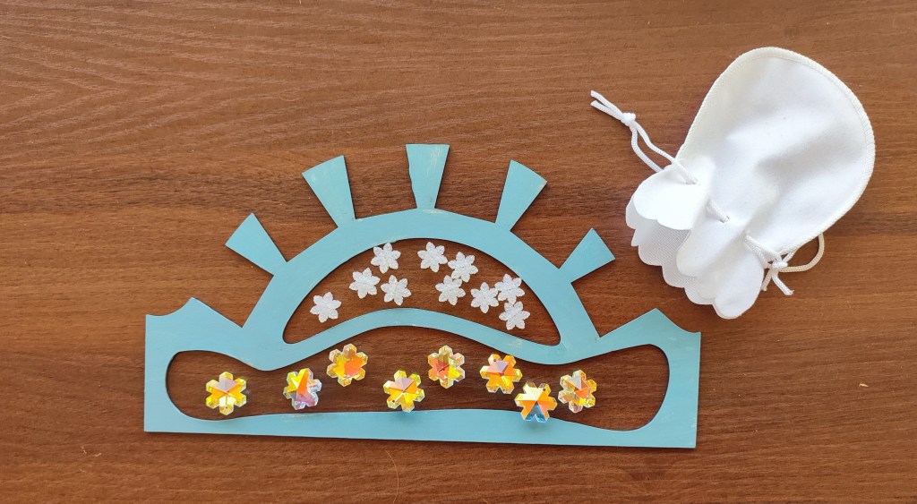 a fell shaped player board containing some tokens in its 2 slots, as well as a white pouch